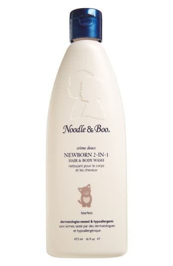 Cream-colored bottle of Noodle & Boo Newborn 2-in-1 Hair & Body Wash with a blue flip-top cap, featuring a silhouette design and text indicating it's tear-free and suitable for sensitive skin.