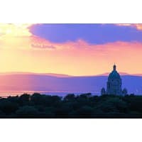 Sunset view of Lancaster House Hotel with distant hills, silhouetted trees, and a domed building under a colorful sky.