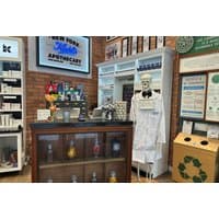 Kiehl's beauty counter with skincare products, skeleton in lab coat, and promotional signage in a brick-walled store.