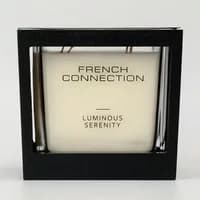 French Connection candle in black square holder with "Luminous Serenity" label, white wax, and wooden wicks.
