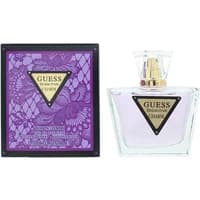 Clear glass bottle with gold cap, purple liquid, and triangular label; purple floral box beside it.