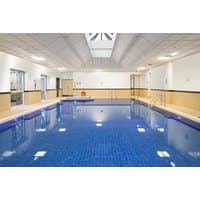 Indoor swimming pool with blue tiles, surrounded by beige walls and a skylight ceiling at Crowne Plaza Glasgow.