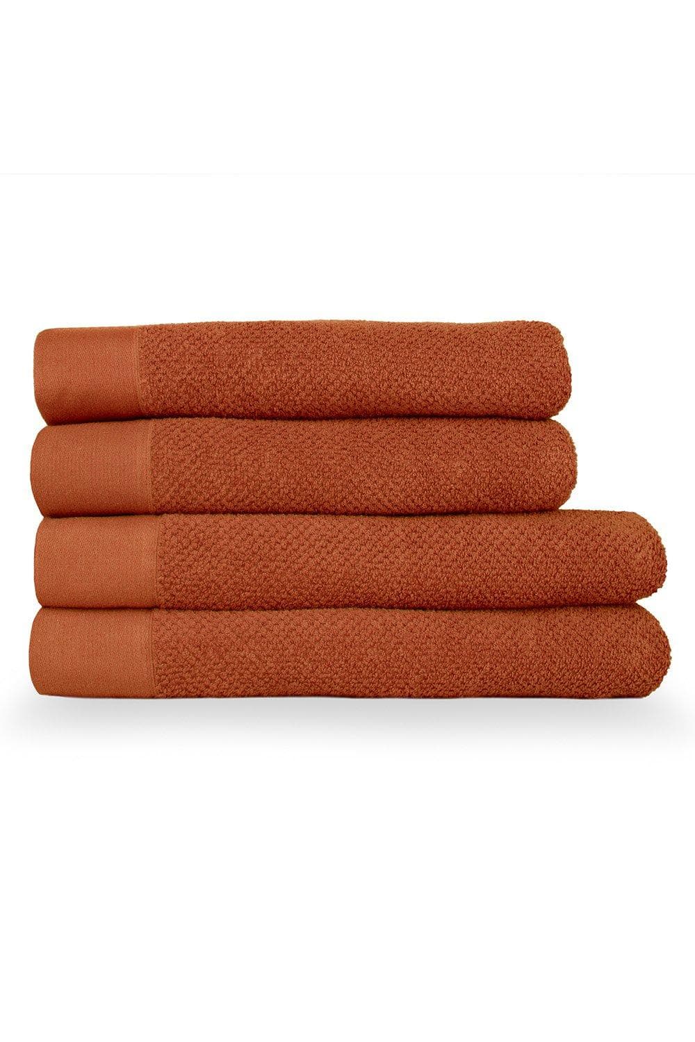 Four stacked bath towels in a warm terracotta color, featuring a textured weave design and smooth cotton panels, showcasing a cozy and stylish bathroom accessory.