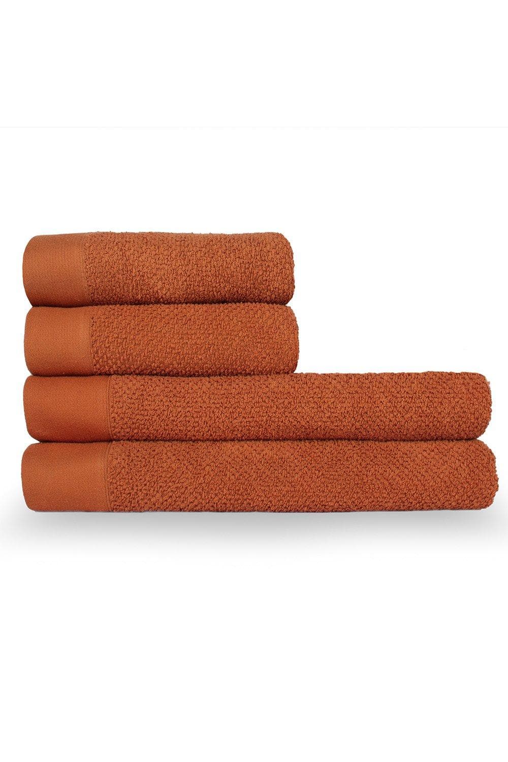 Four textured weave cotton towels in a warm terracotta color, featuring a soft, absorbent surface and contrasting smooth edges, stacked neatly.