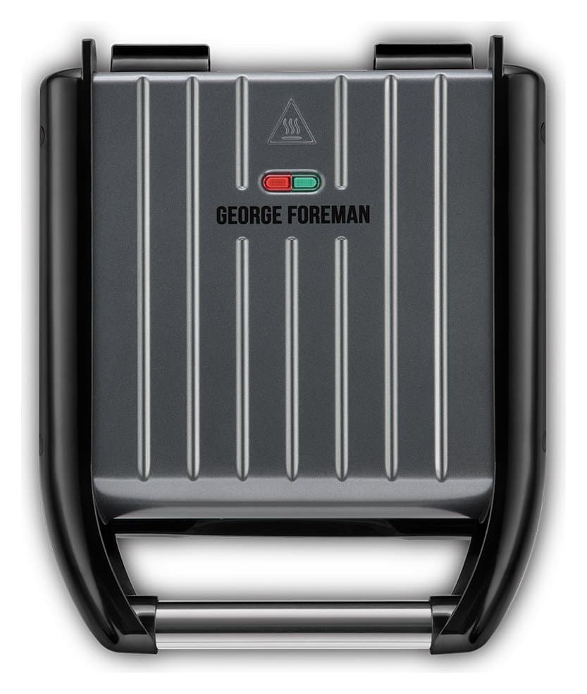 Small grey steel grill with a ribbed cooking surface, featuring a black handle and red/green indicator lights, branded with "GEORGE FOREMAN" on the top.