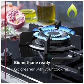 Black 90cm Neff T29TS79N0 N90 gas hob featuring five burners, including a prominent wok burner with blue flame, set against a backdrop of cooking ingredients.