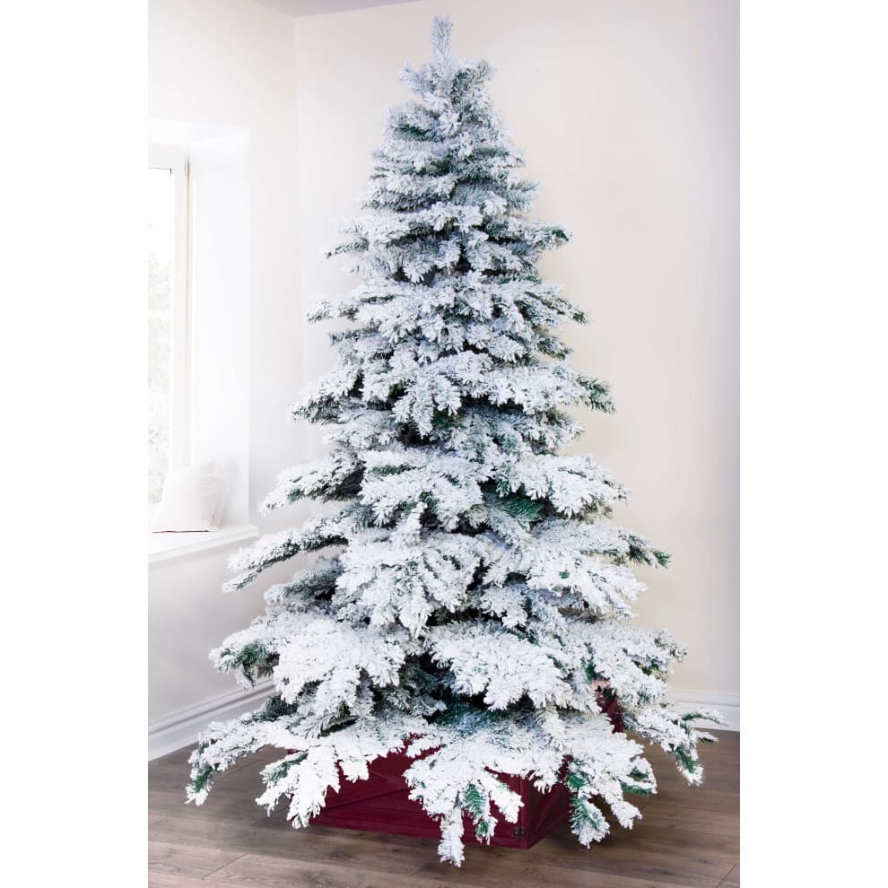 Snowy white fir Christmas tree, 8 feet tall, with frosted branches and green tips, set in a red base, displayed in a bright room with natural light.