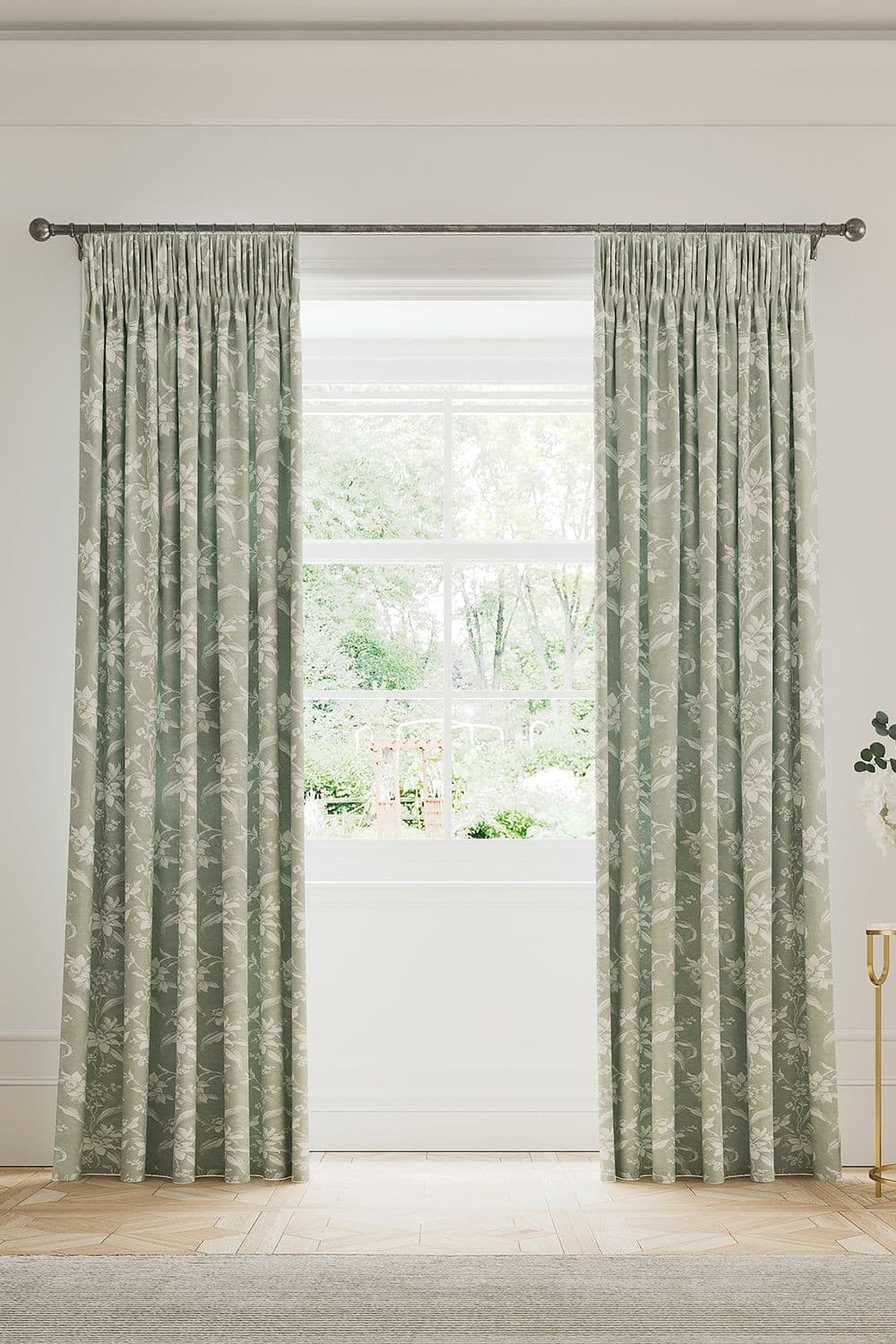 Soft green cotton-lined curtains featuring a delicate daffodil pattern, elegantly gathered at the top, framing a bright window with a view of greenery outside.