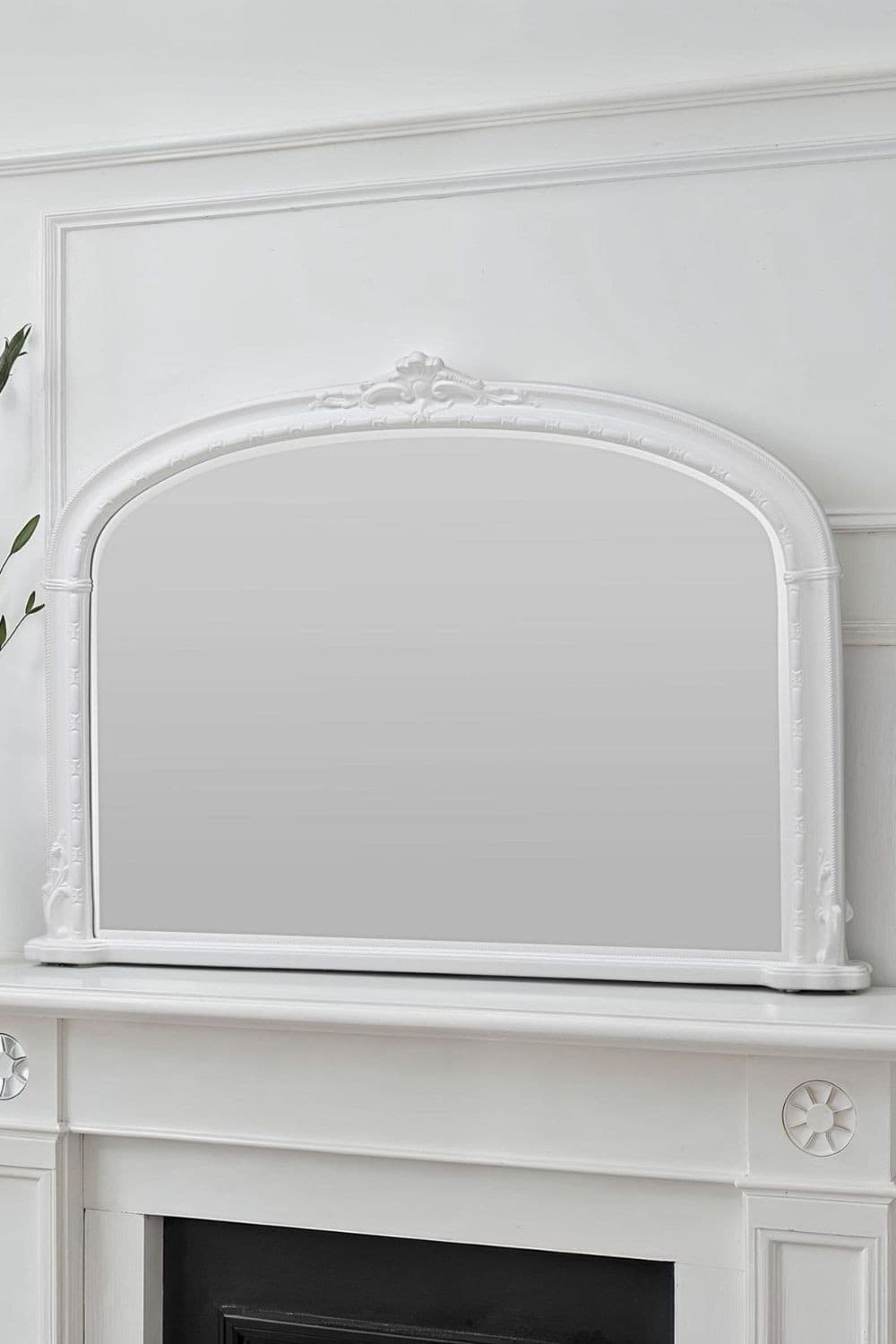 Victorian-style overmantle mirror in white, featuring an arched top and intricate detailing, measuring 127cm wide by 89cm high, elegantly mounted above a fireplace.