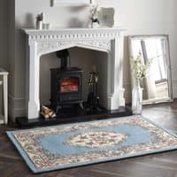 Blue circular rug with intricate floral patterns and beige border, placed in a cozy living room setting.