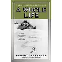 Book cover for "A Whole Life" by Robert Seethaler, features a skier on a snowy slope with green and gray borders.
