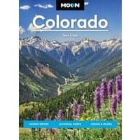 "Moon travel guidebook titled 'Colorado' featuring mountain landscape with purple wildflowers and blue sky."
