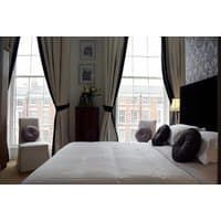 Elegant hotel room with large windows, plush bedding, dark curtains, and decorative pillows at Georgian Townhouse Hotel.