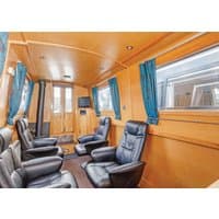 Interior of "Gloria" narrowboat by Hoseasons, featuring black leather recliners, wood paneling, and blue curtains.