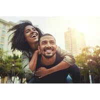 Psychic reading session image with smiling couple outdoors, woman piggybacking on man, cityscape background.