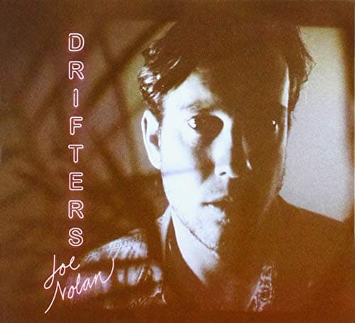 A close-up of a man with dark hair and a serious expression, featuring the word "DRIFTERS" in bold pink letters and "Joe Nolan" in a cursive style below.