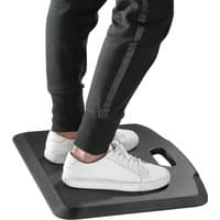 Black ProperAV anti-fatigue mat with rubberised-gel foam, beveled edges, and built-in handle, supporting feet in sneakers.
