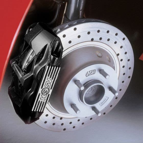 Black wheel brake caliper with silver accents mounted on a perforated brake disc, showcasing a sleek, heat-resistant design ideal for automotive applications.