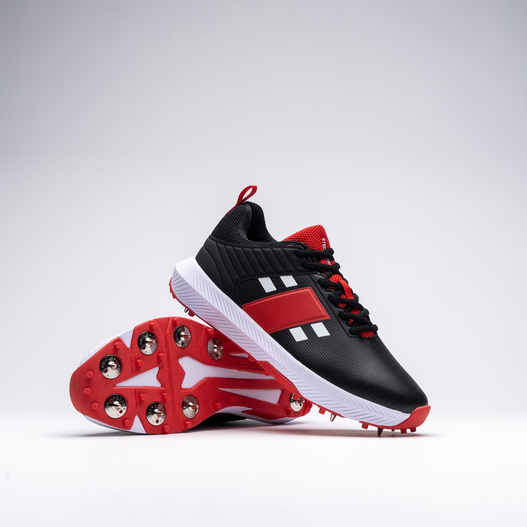Gray-Nicolls Players 3.0 black adult spike shoes featuring a sleek black upper, red accents, white stripes, and a durable white sole with metal spikes for traction.