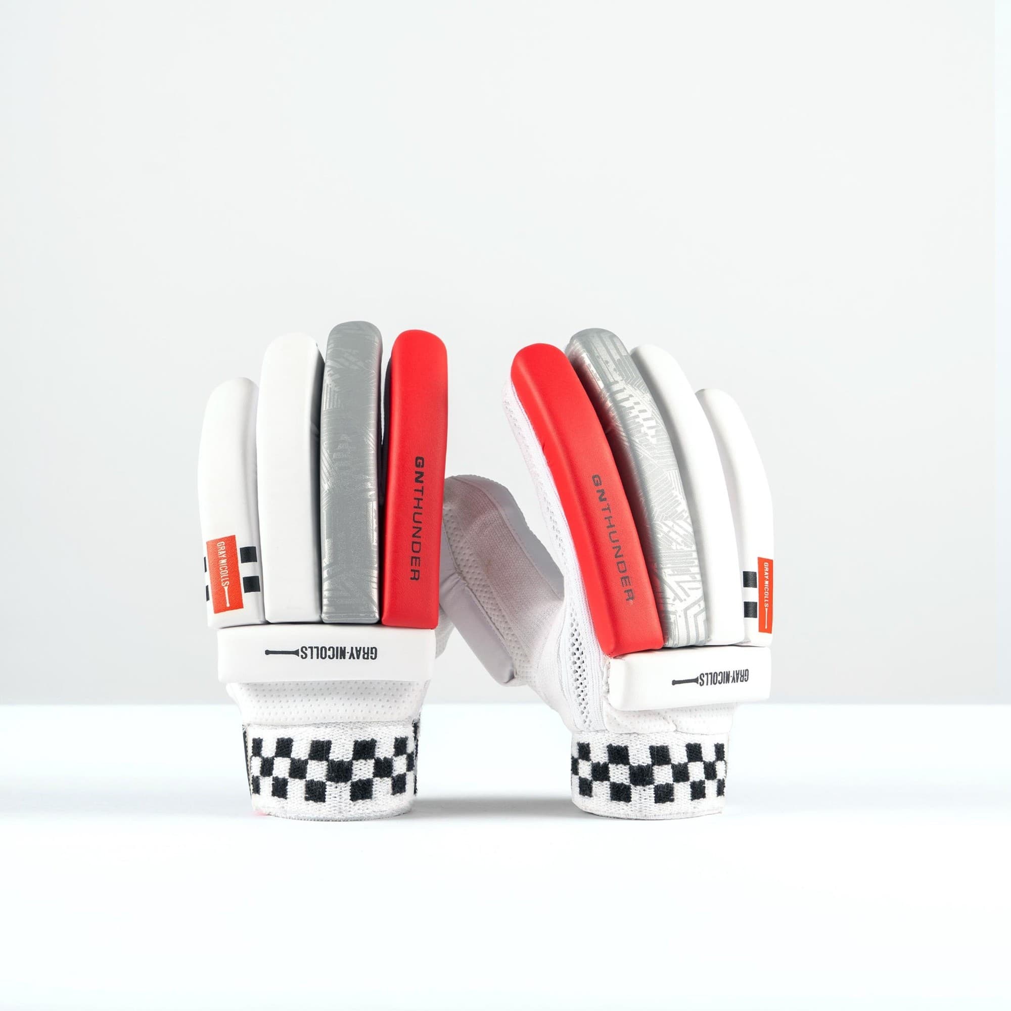 Gray-Nicolls Thunder junior batting gloves in white, featuring gray and red accents, padded fingers, a textured grip, and a checkered wristband for added support.