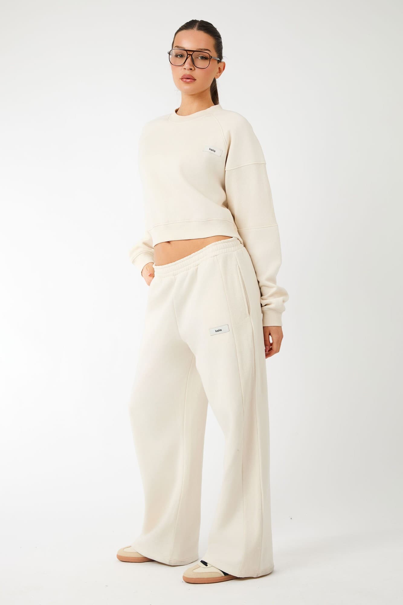 Cream ribbed wide-leg joggers featuring a comfortable elastic waistband and subtle logo detail, paired with a matching cropped sweatshirt.
