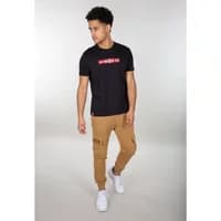Tan Alpha Industries Terry jogging trousers with ribbed cuffs and side pockets, worn by a model with white sneakers.