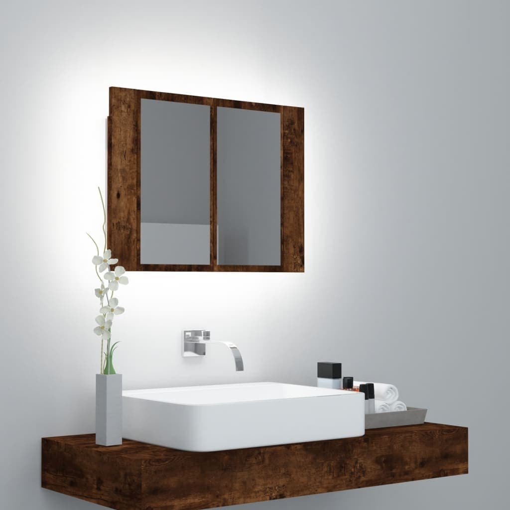 LED mirror cabinet in smoked oak finish, featuring two mirrored doors, mounted above a white sink, with decorative plants and toiletries on a wooden shelf below.