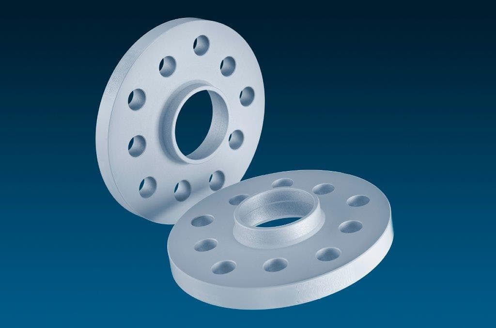 Silver aluminum wheel spacers with a 20mm thickness, featuring a central hole and four holes around the perimeter for secure fitting, designed for track widening.