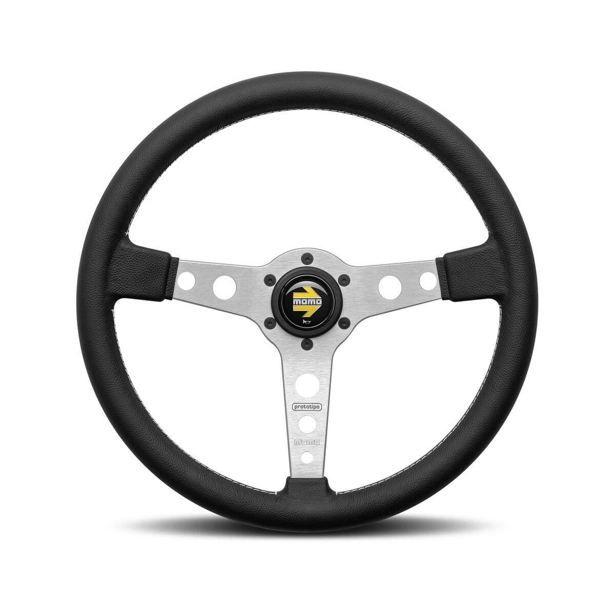 Black leather steering wheel with a 320mm diameter, featuring a silver aluminum center and three spokes, highlighted by circular cutouts and a Momo logo at the hub.