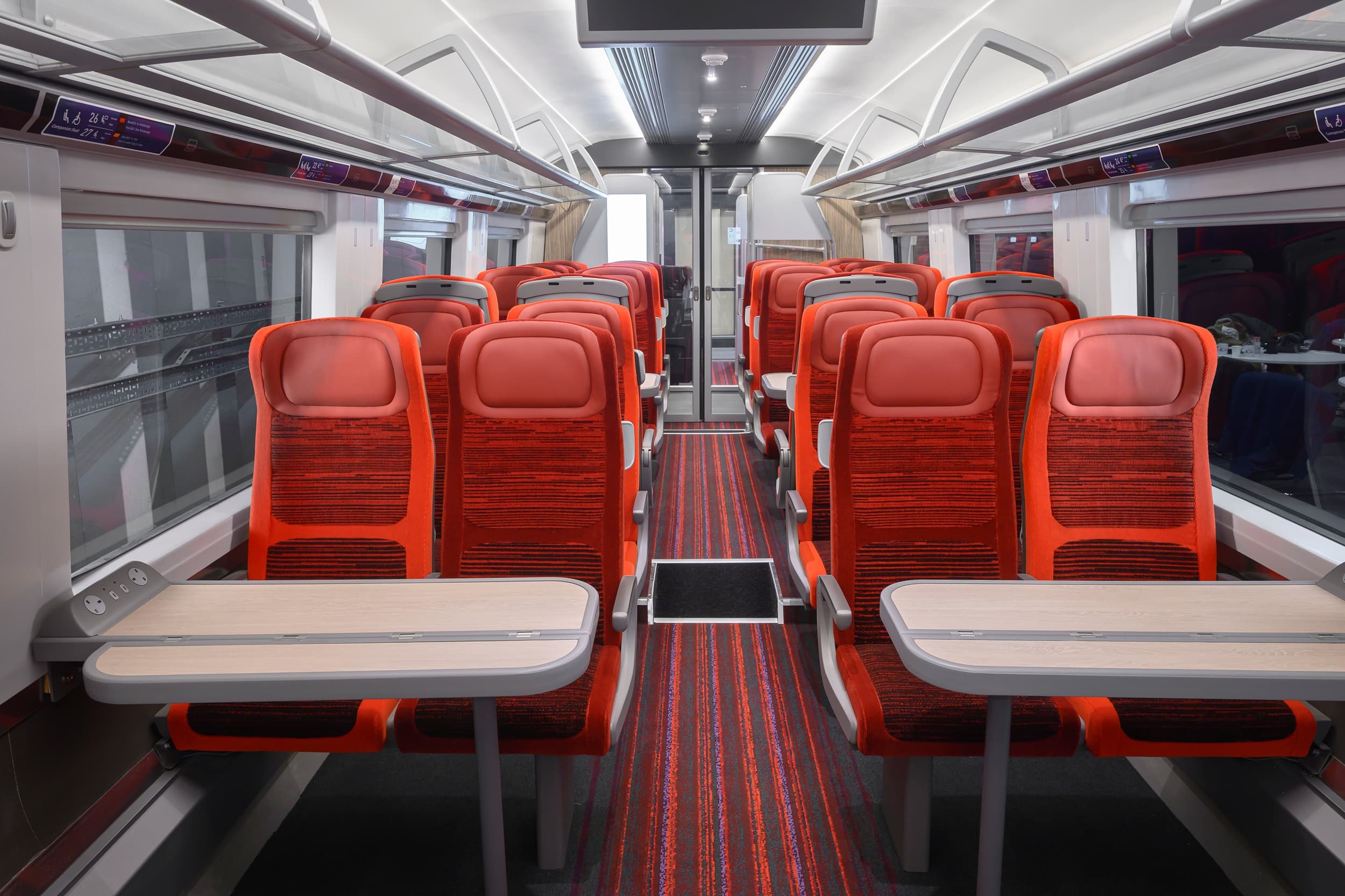 Modern train interior featuring red seating and sleek design, showcasing comfort and style for East Coast Main Line travel.