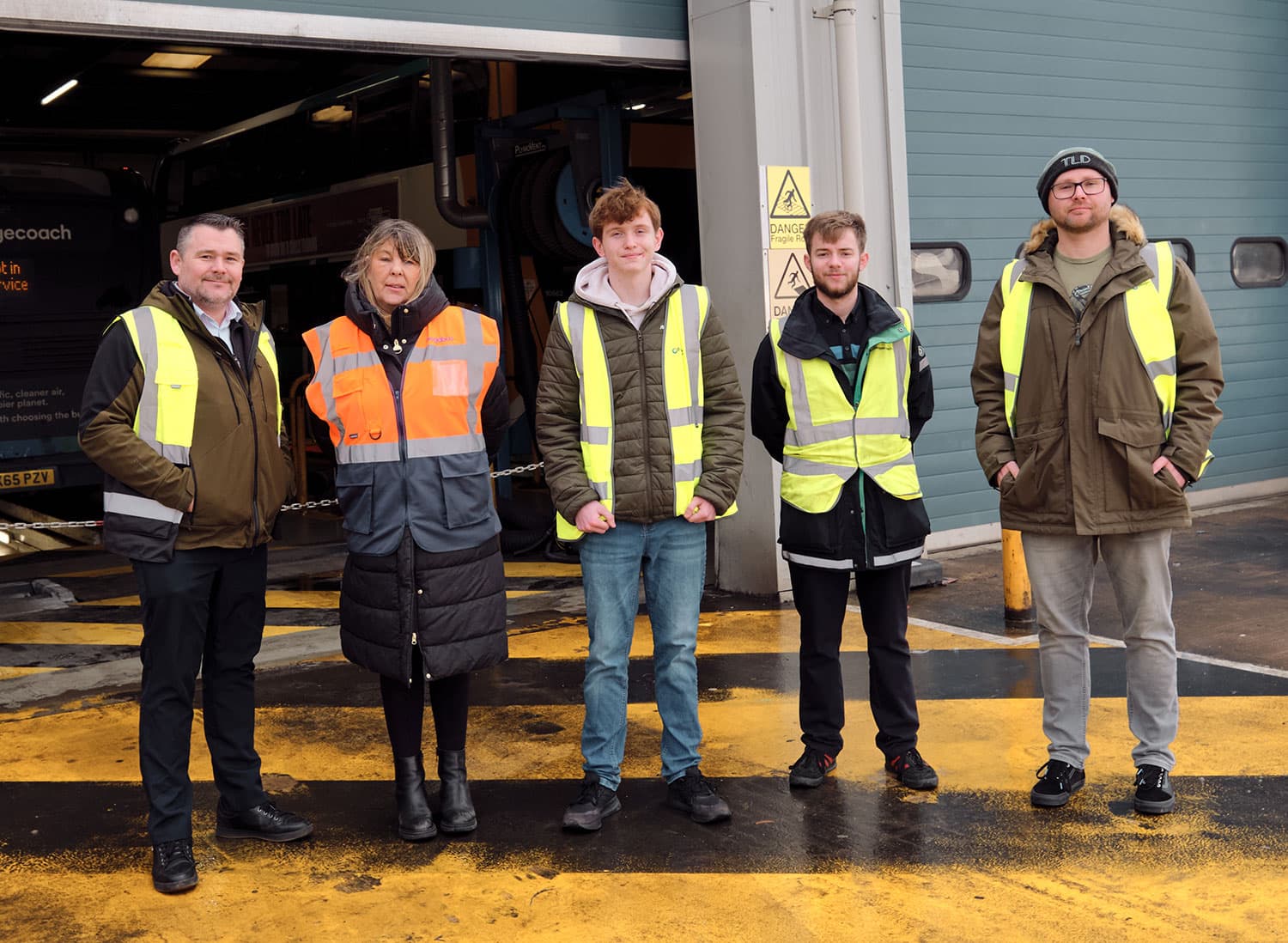 Five individuals in high-visibility vests stand outside Stagecoach's Barnsley Depot, showcasing a modern industrial setting.