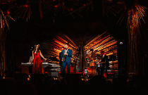 A jazz band performs on stage in a vibrant venue, with colorful lights and an intimate audience enjoying the music.