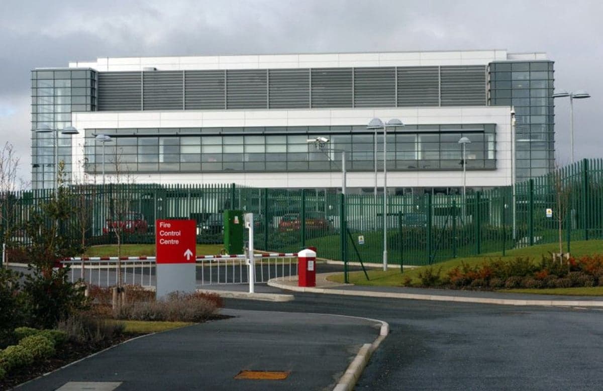 Modern glass-fronted building with green fencing and landscaped gardens, located in Wakefield, Yorkshire.