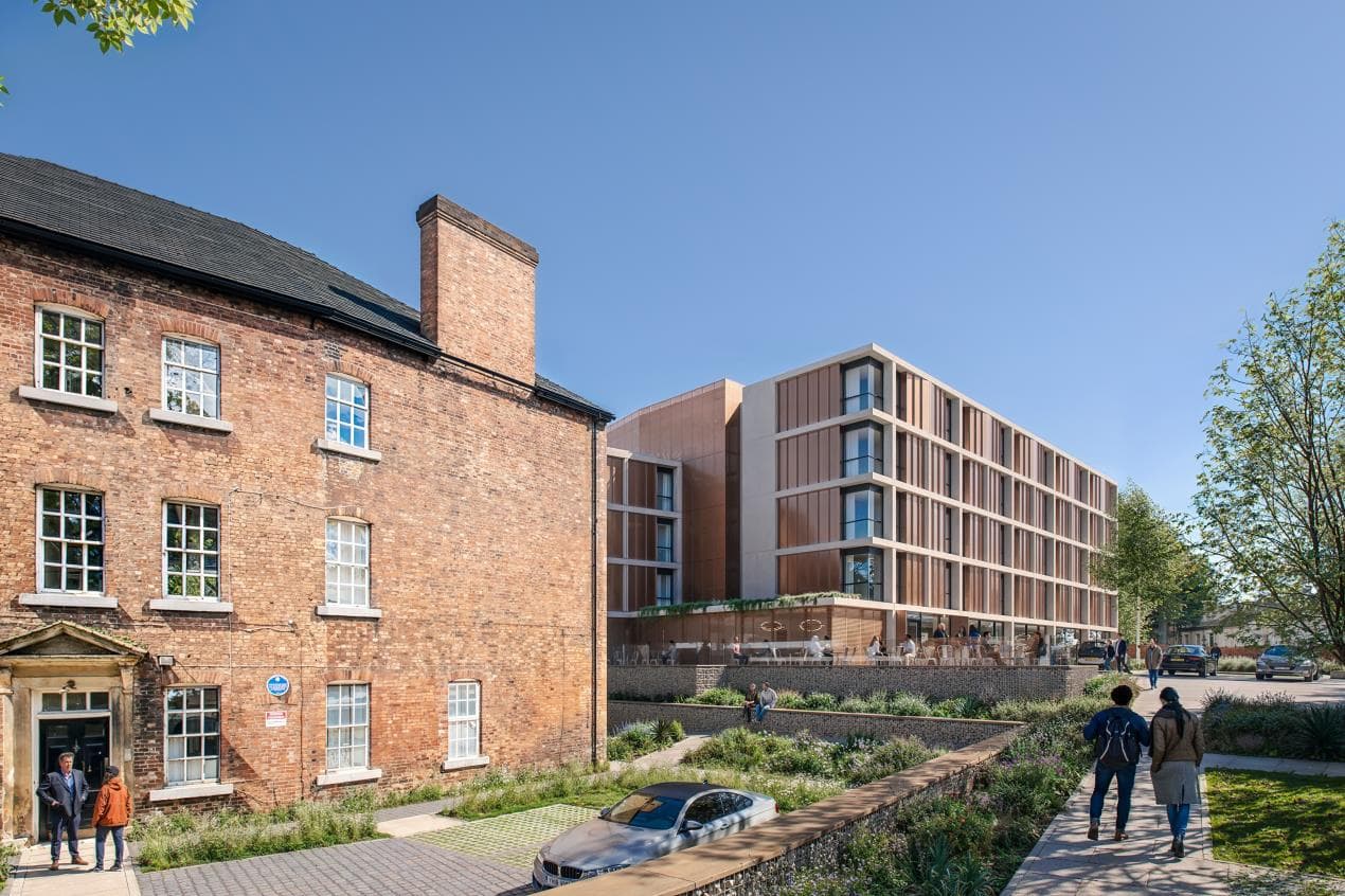 Modern hotel building alongside a historic brick structure in Wakefield, with pedestrians walking through green landscaping.