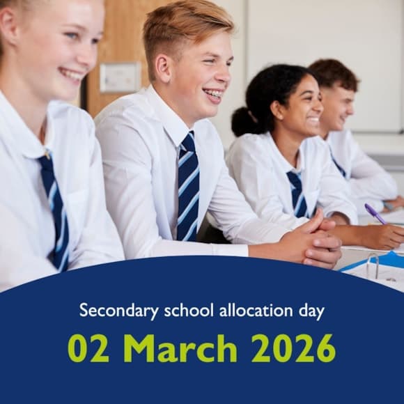 Four smiling students in school uniforms sit at a desk, eagerly awaiting secondary school allocation results.