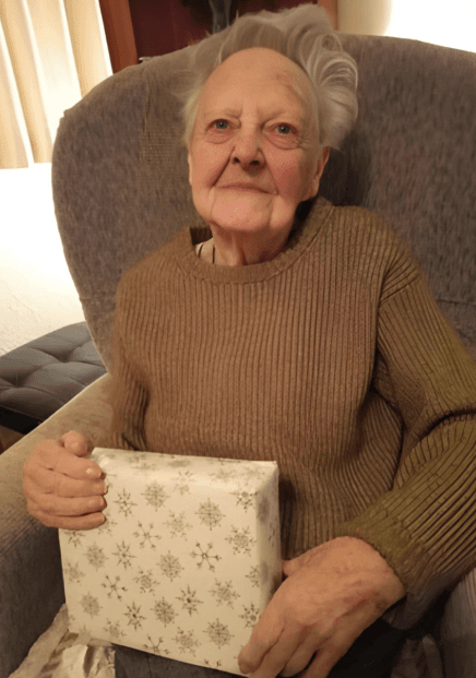 Elderly person sitting in chair holding a wrapped gift