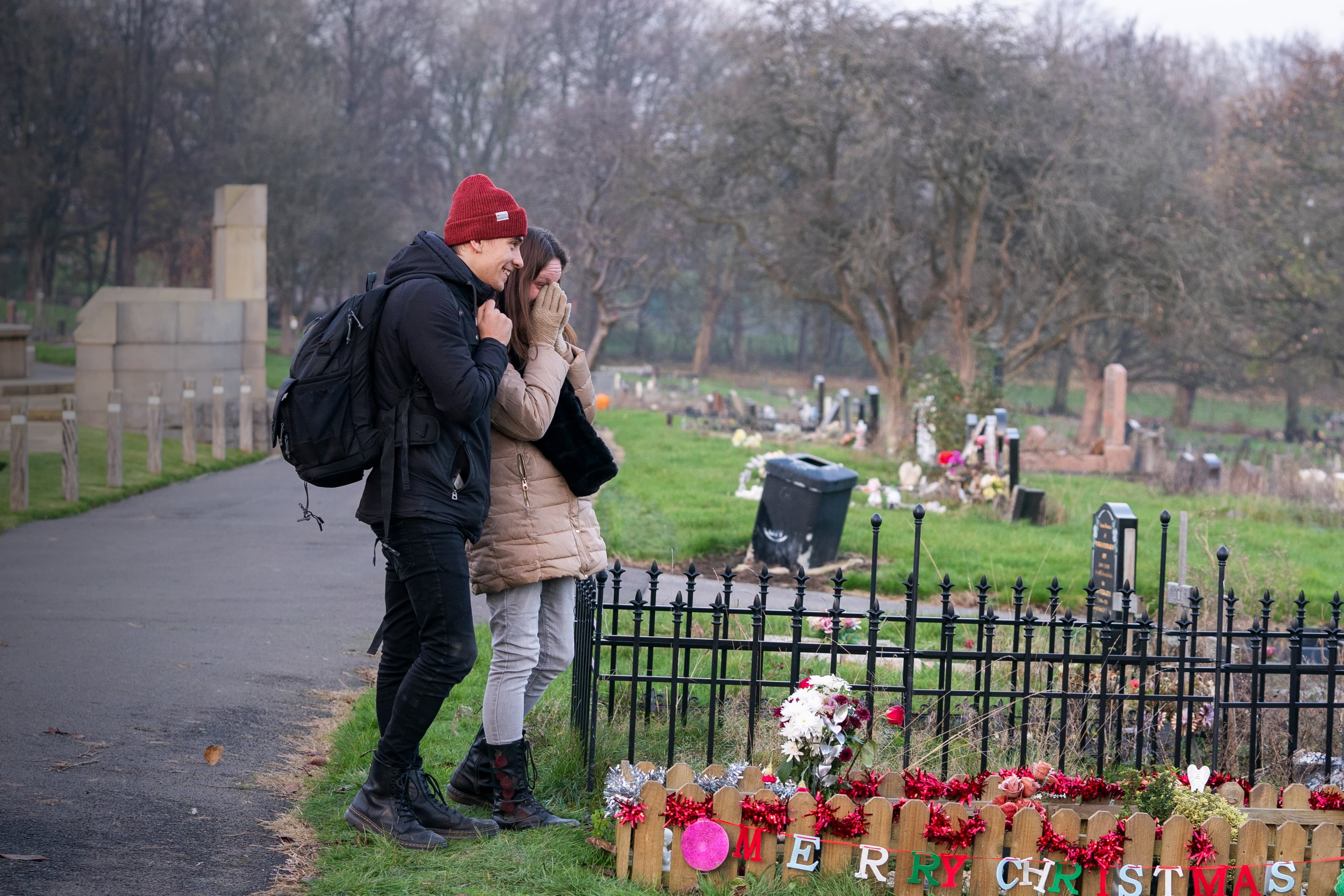 Couple visiting decorated grave in winter cemetery
