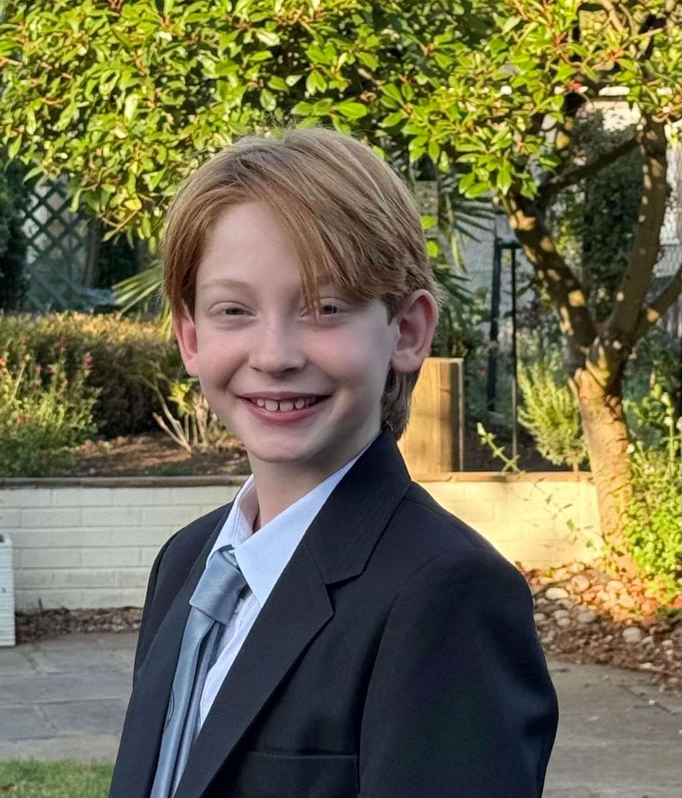 Smiling young person in a suit standing in a garden