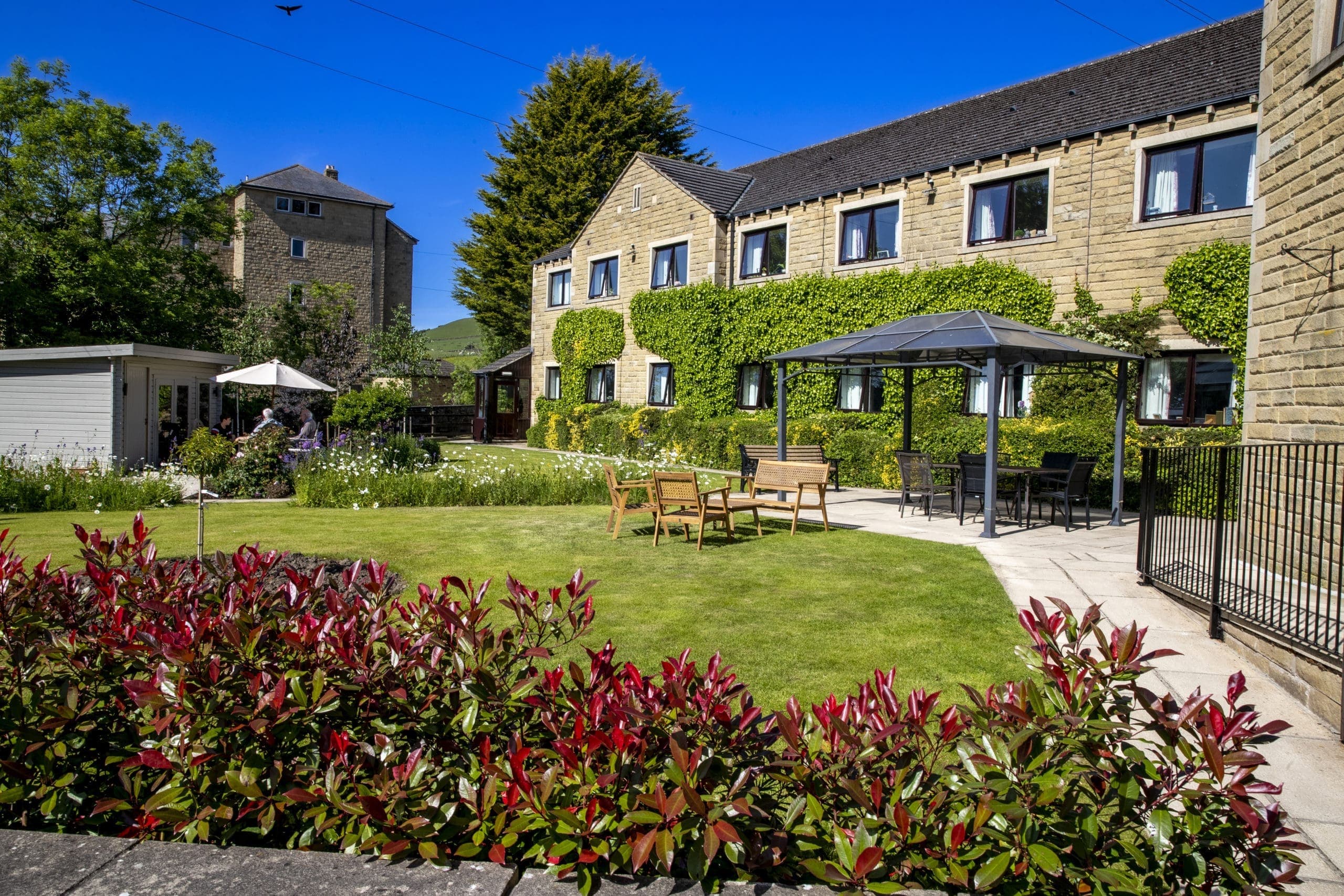 Charming stone hotel with ivy, garden seating, and blue sky
