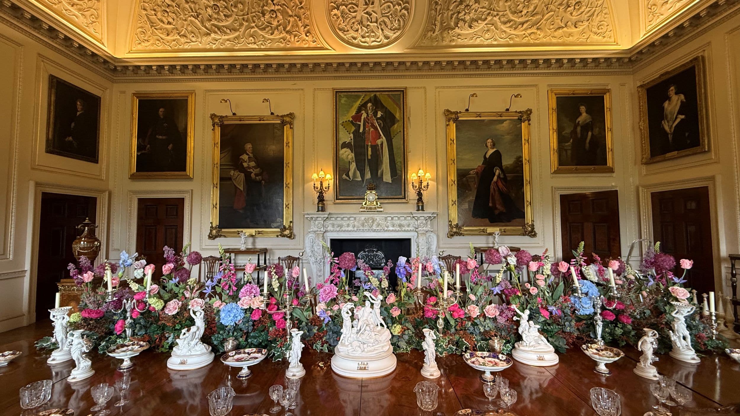 Ornate dining room with floral centerpiece and classical paintings
