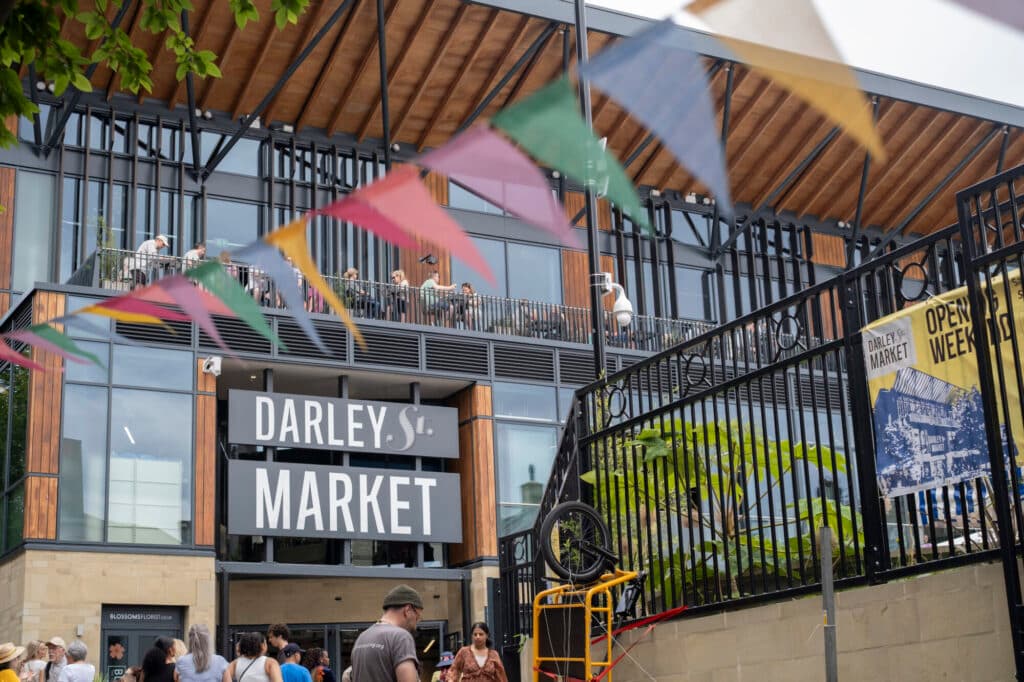 Modern market entrance with colorful bunting and people