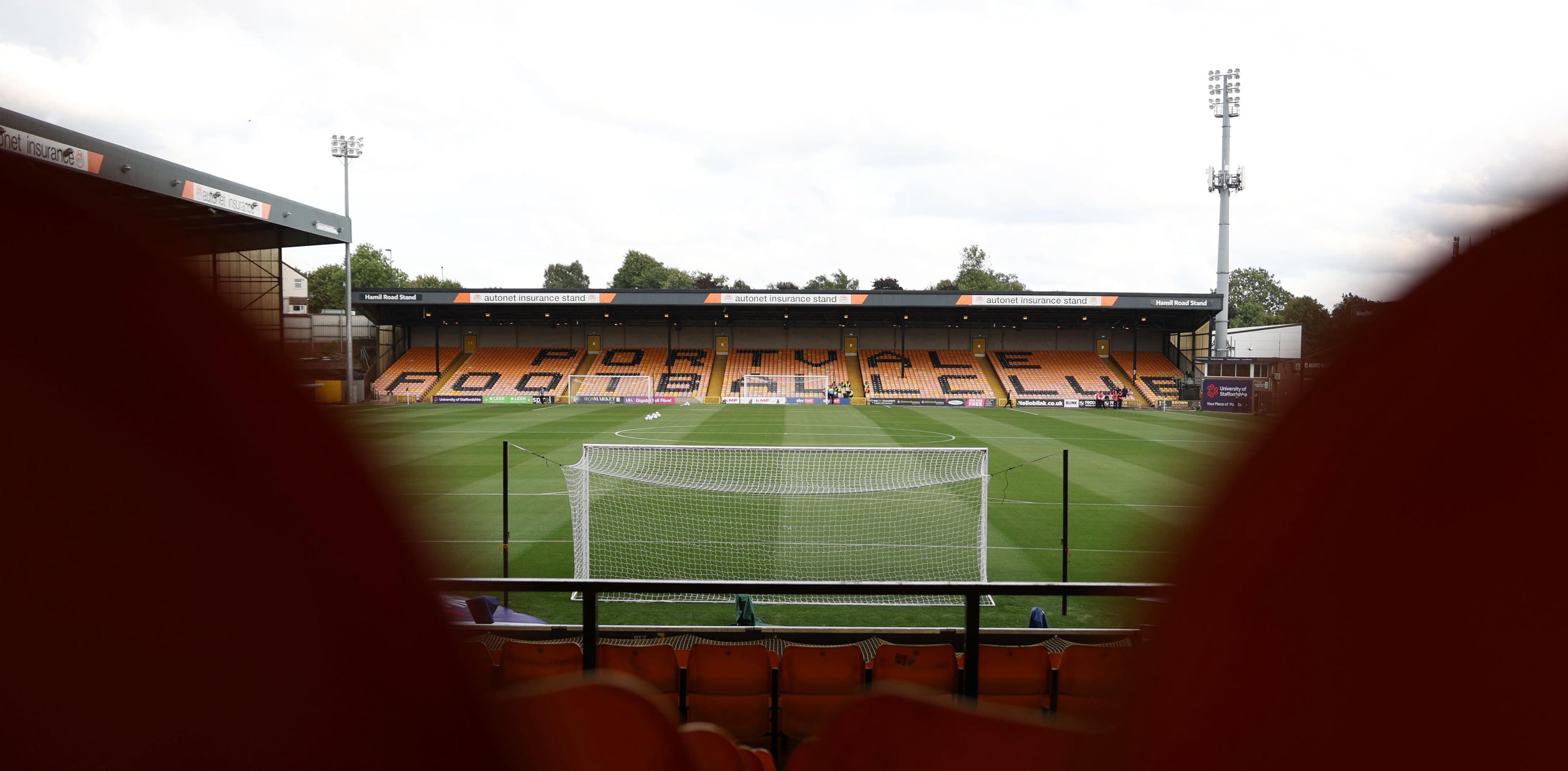 Empty football stadium with orange seats and goalpost