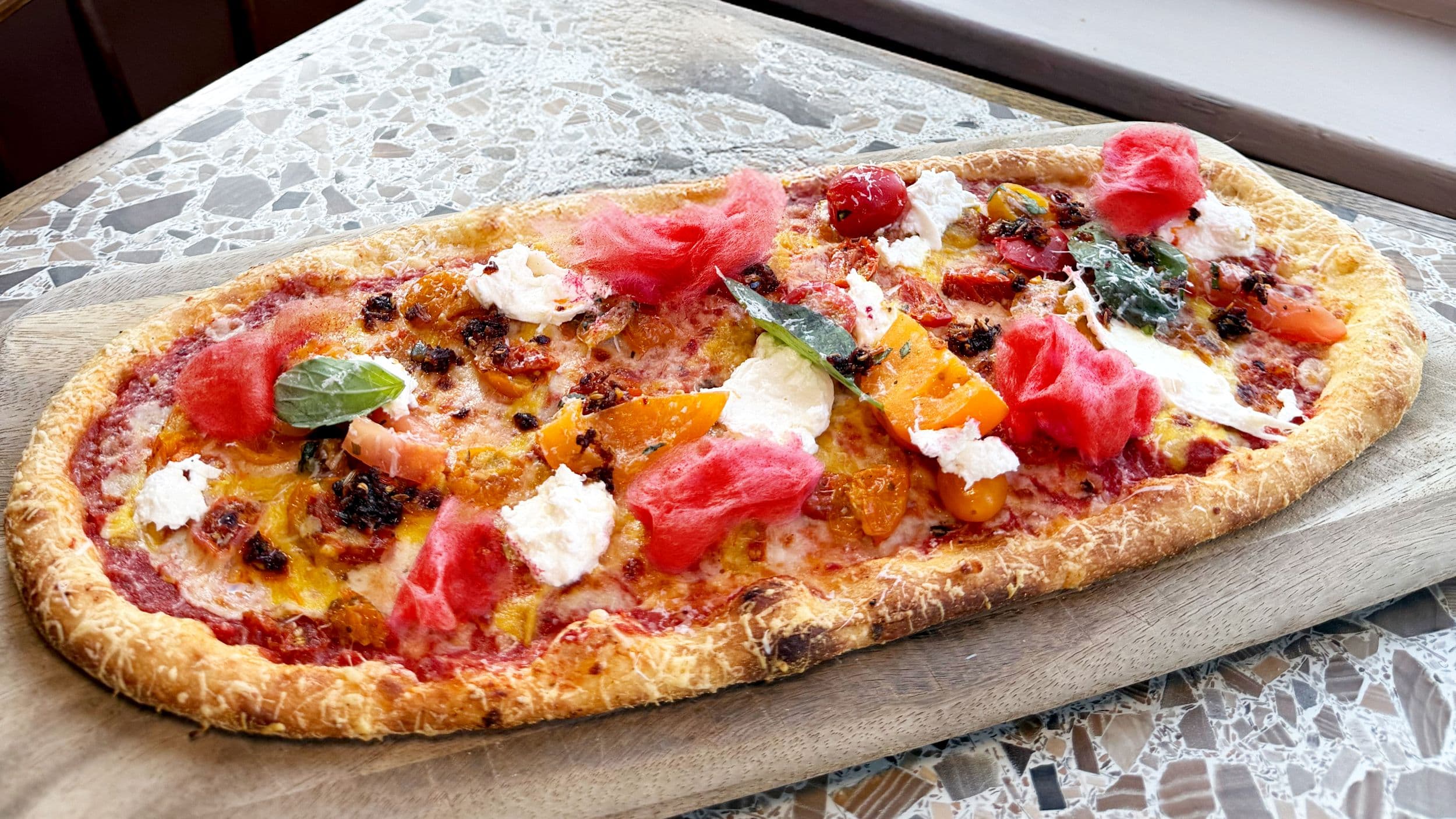 Gourmet pizza with colorful toppings on wooden board