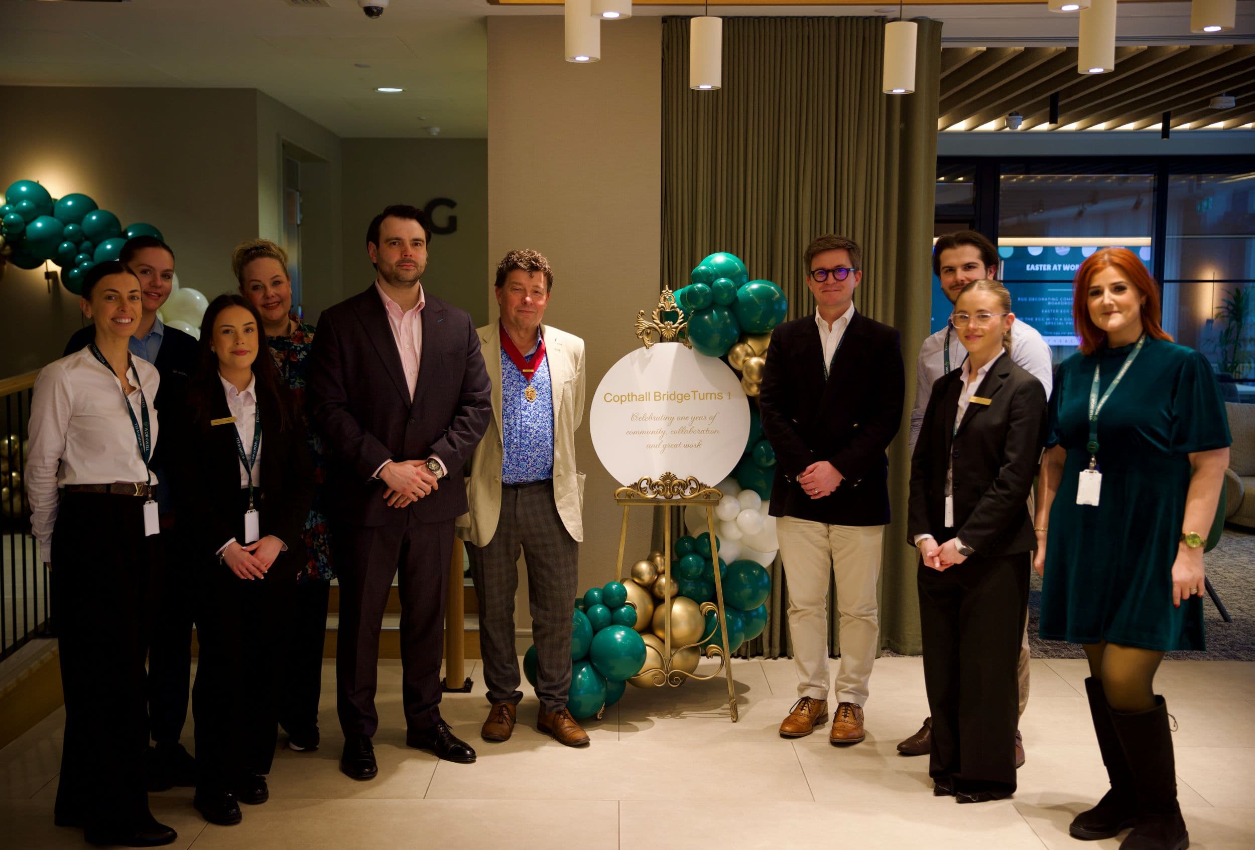 Group of people in formal attire posing near hotel lobby decorations