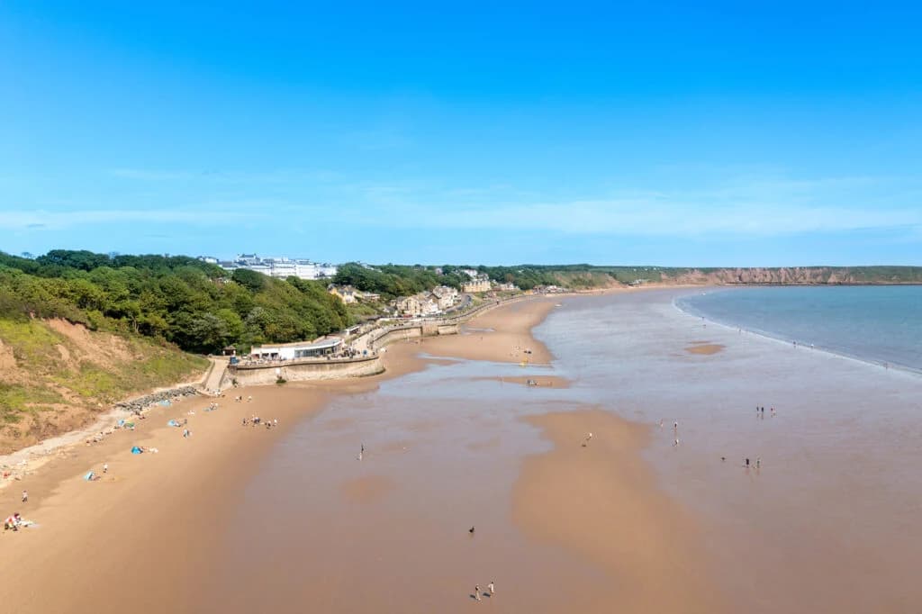 Filey sandy beach with cliffs and blue sea under clear sky