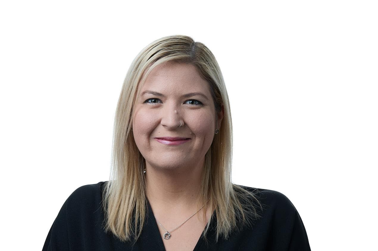 Smiling person with blonde hair in a black top