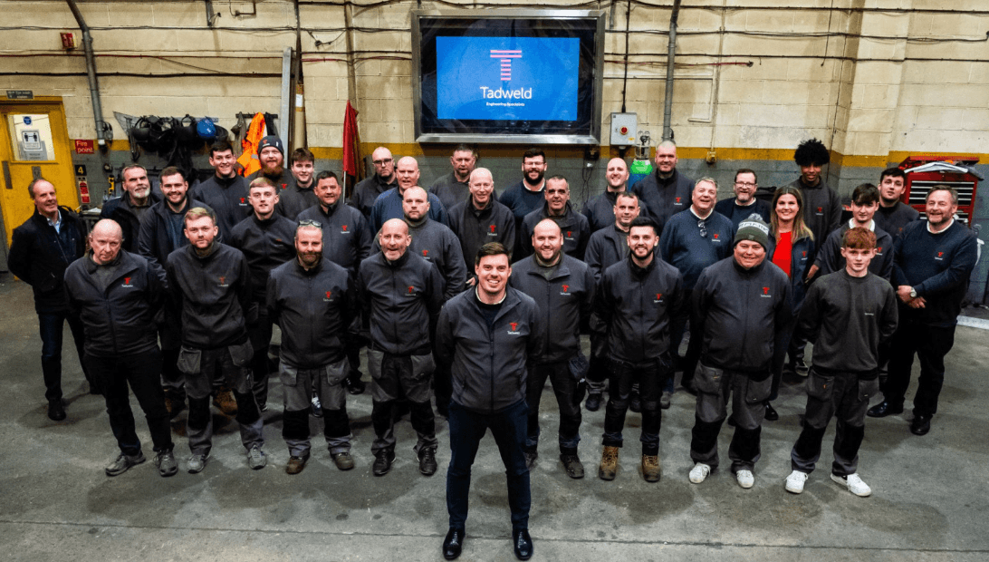 Group of workers in uniforms smiling inside a workshop
