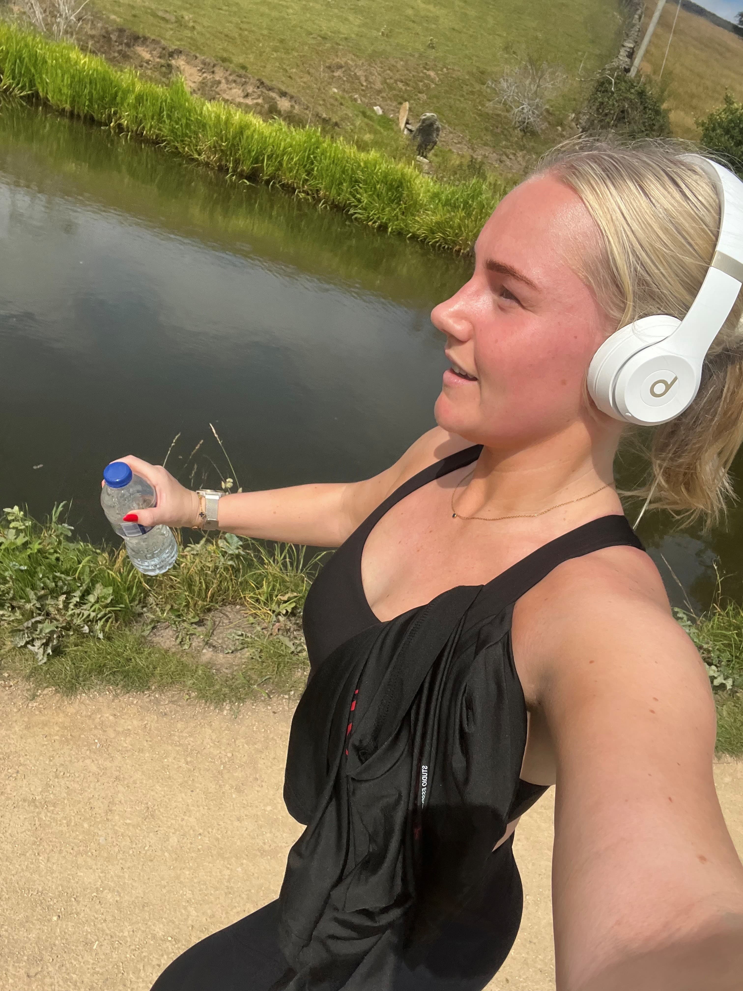 Woman jogging by a canal in sunny Yorkshire countryside