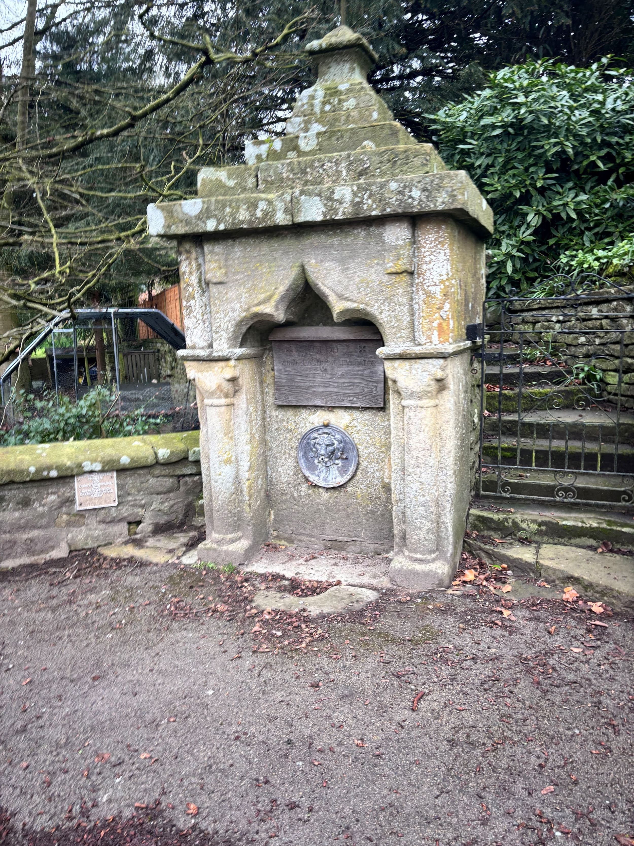 Historic stone well with arched canopy in wooded area