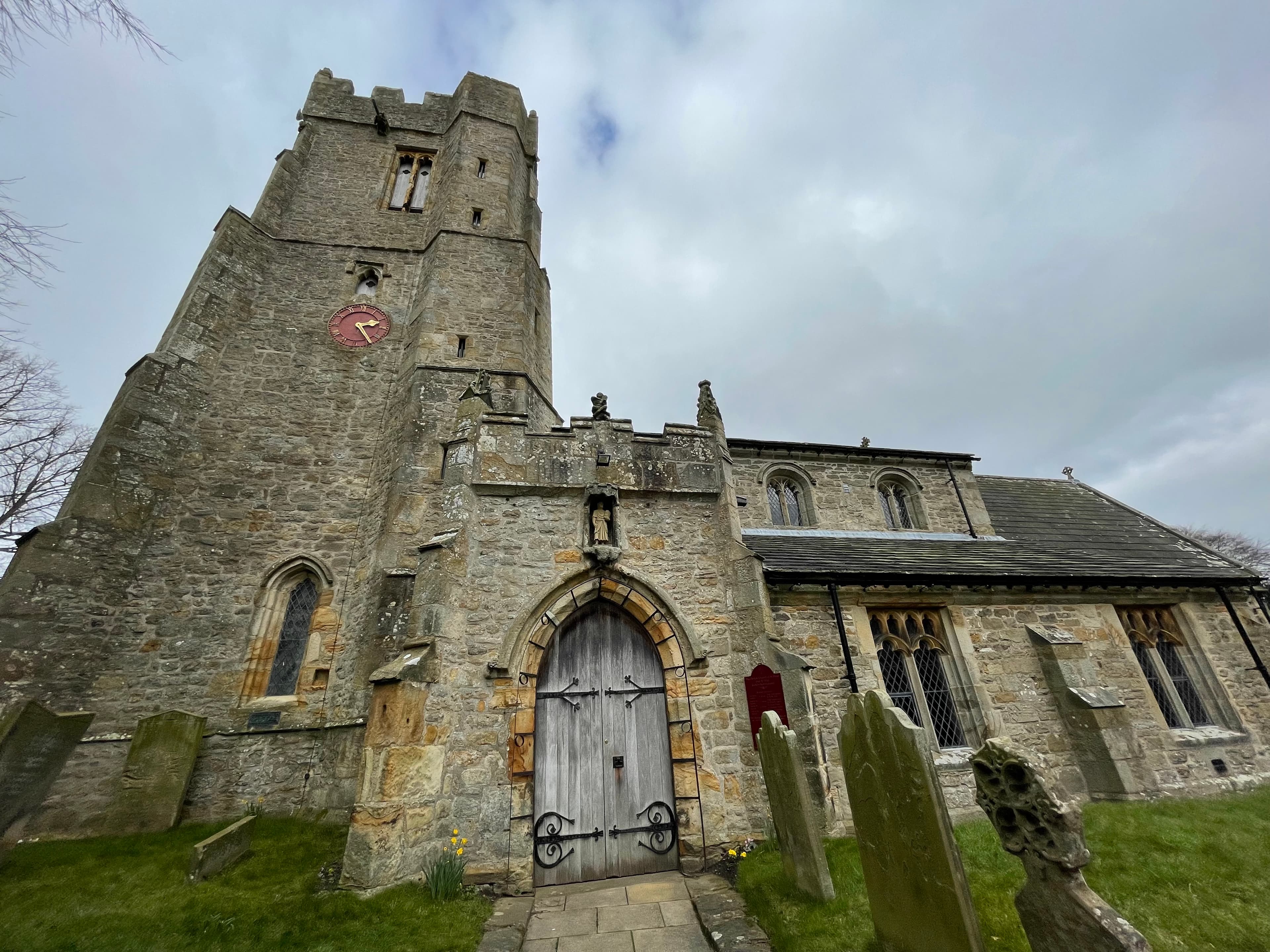 Medieval stone church with a clock tower and graveyard